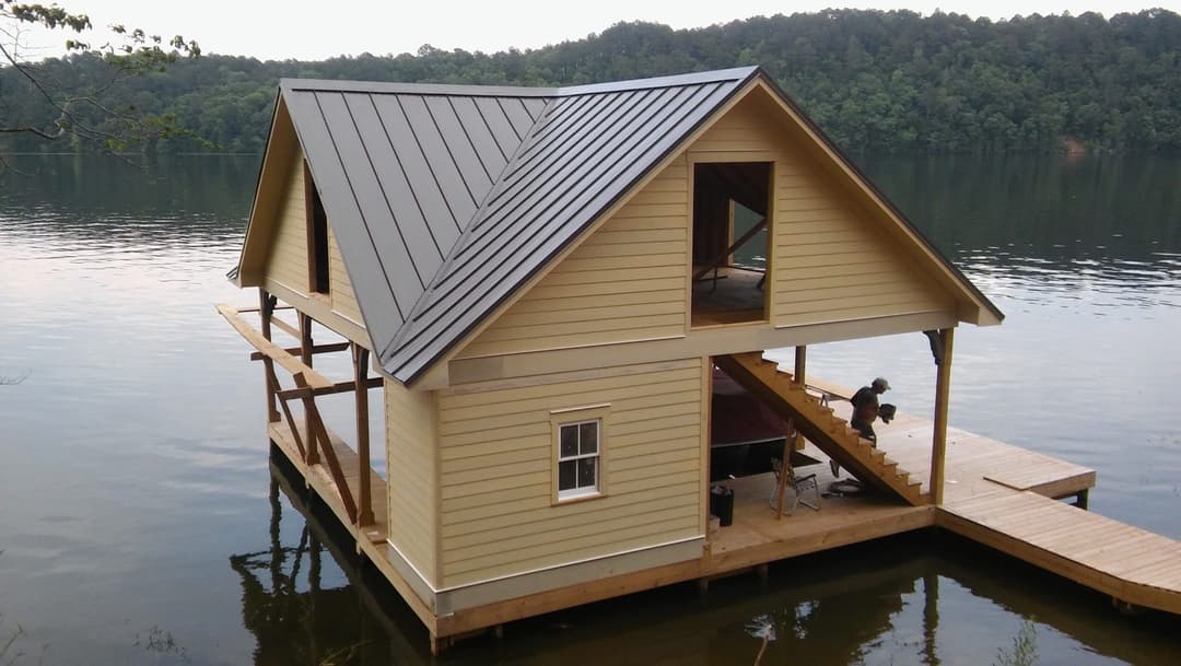 Lakeside cottage with a modern design, featuring a metal roof and wooden dock.