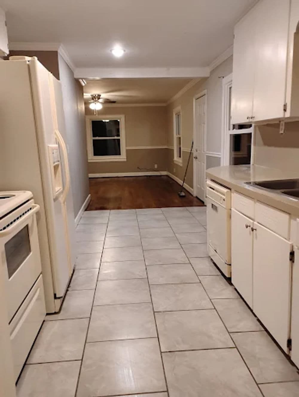 Modern kitchen view with tile flooring, white appliances, and an open layout to the dining area.