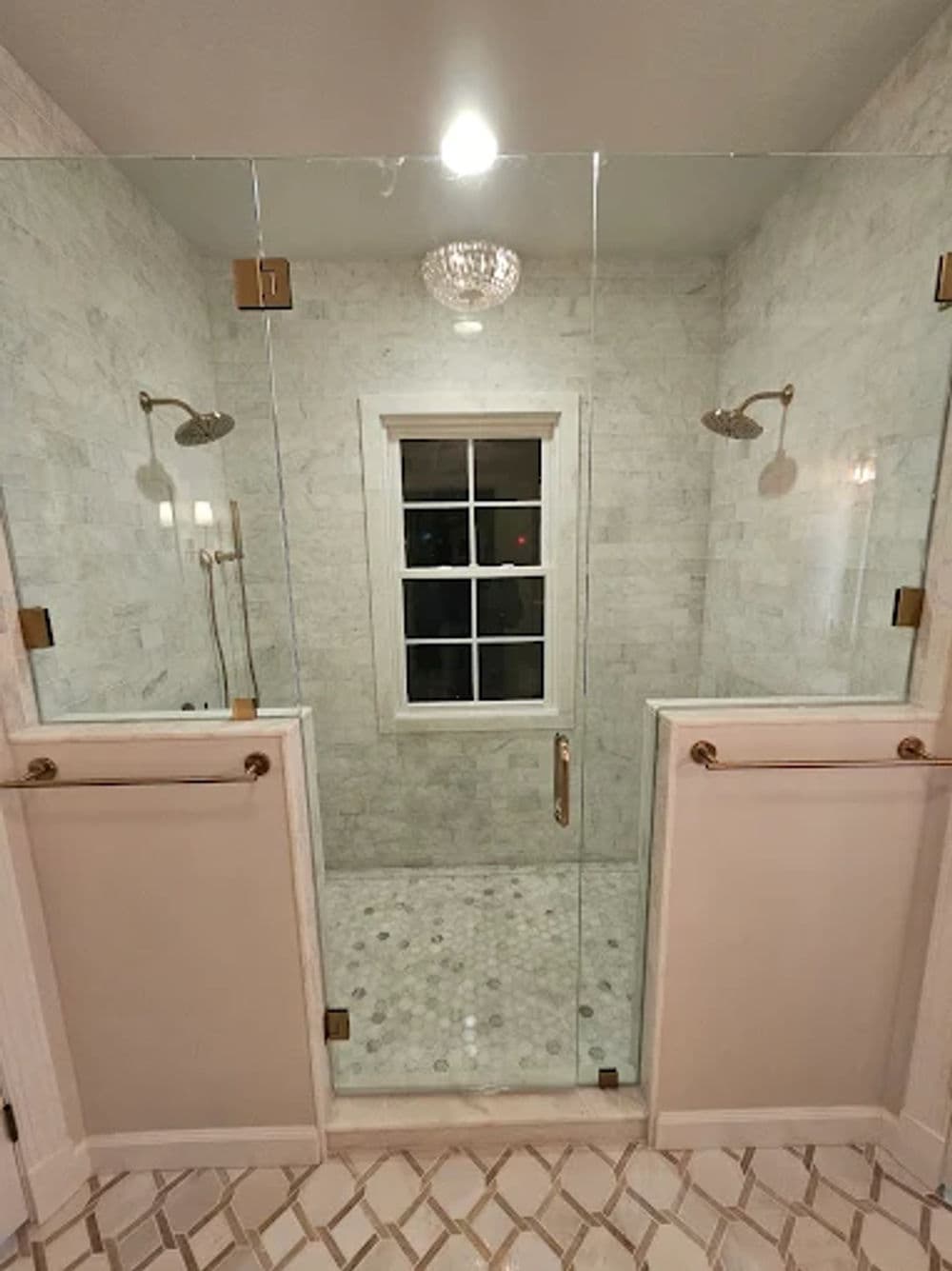 Elegant modern shower with glass walls, marble tile, and stylish fixtures. Bright ambiance.
