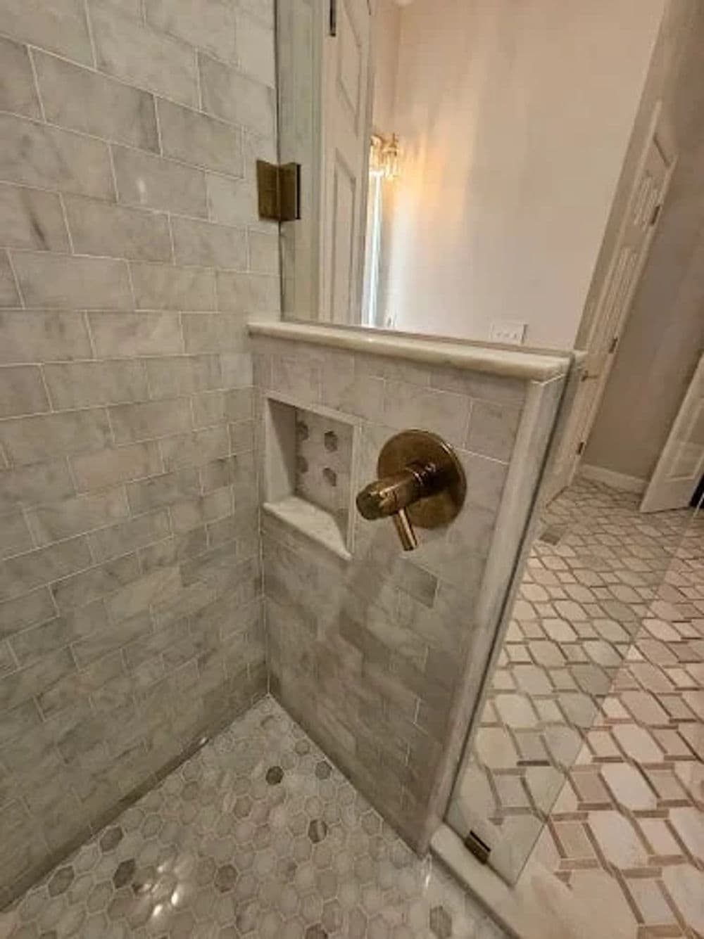 Modern shower with marble tiles, built-in niche, and elegant fixtures in a bright bathroom.