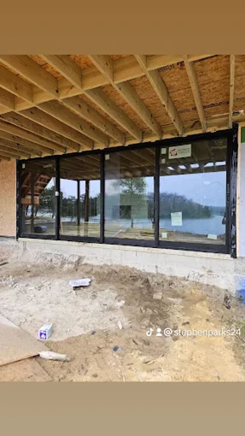 Newly installed floor-to-ceiling windows in a construction setting by a lake.