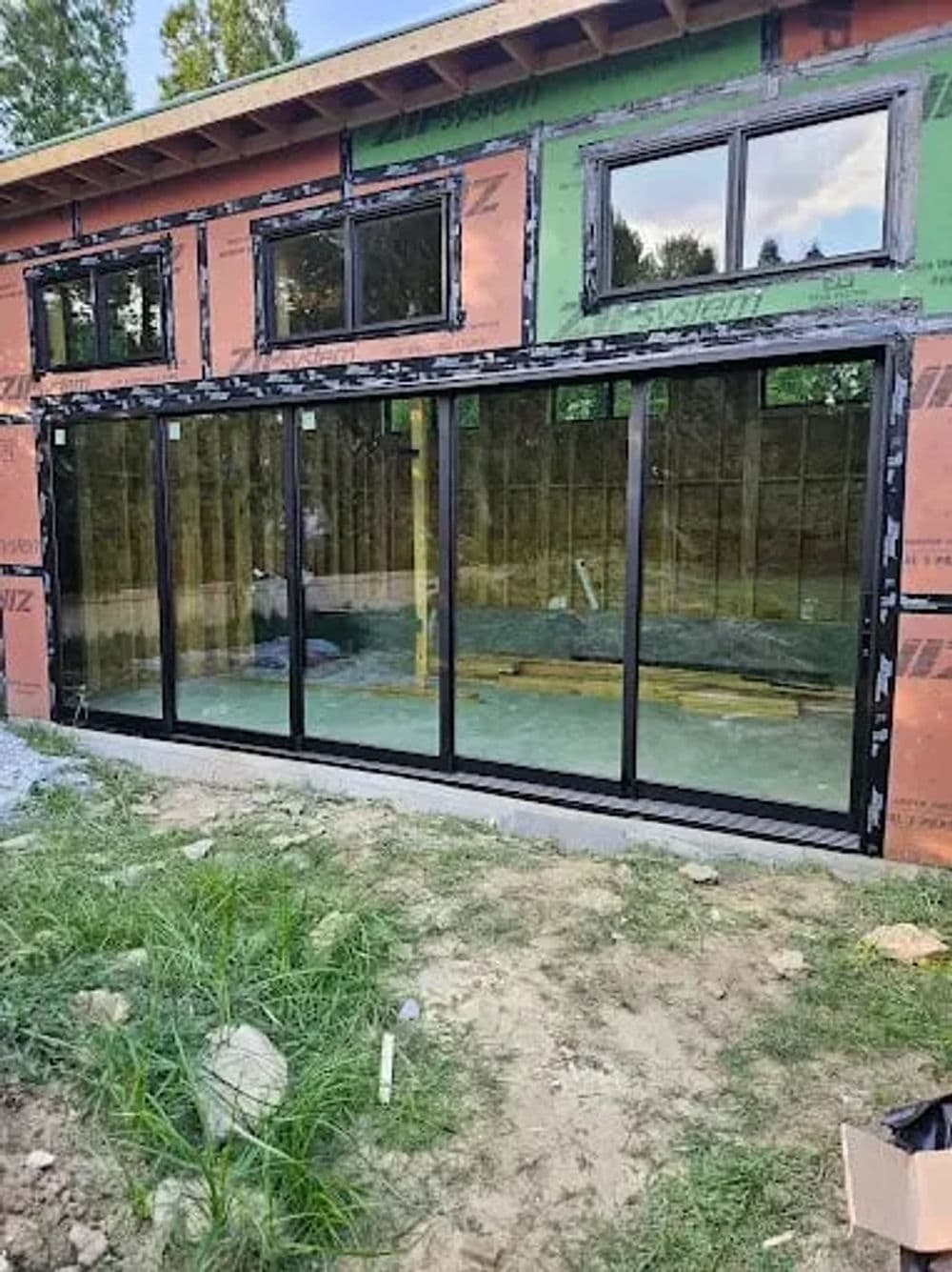 Modern black sliding glass door installation at a construction site with surrounding drywall.