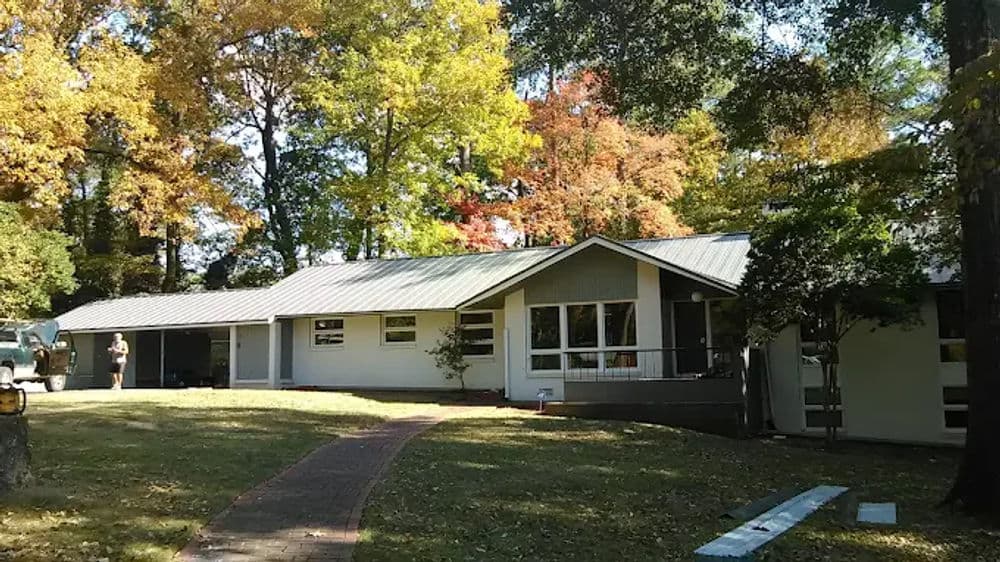 Modern home surrounded by colorful autumn trees and a landscaped lawn.