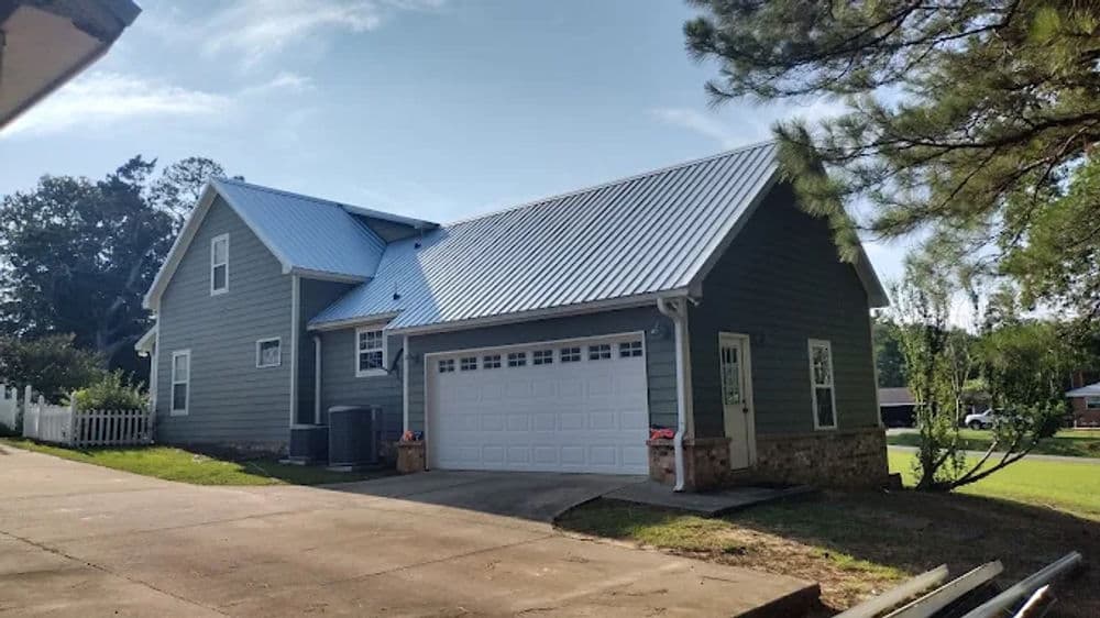 Modern gray house with metal roof and garage set on a spacious driveway.
