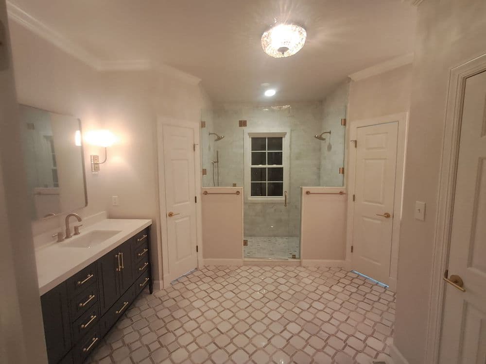 Spacious modern bathroom with double vanities, large shower, and elegant tile flooring.