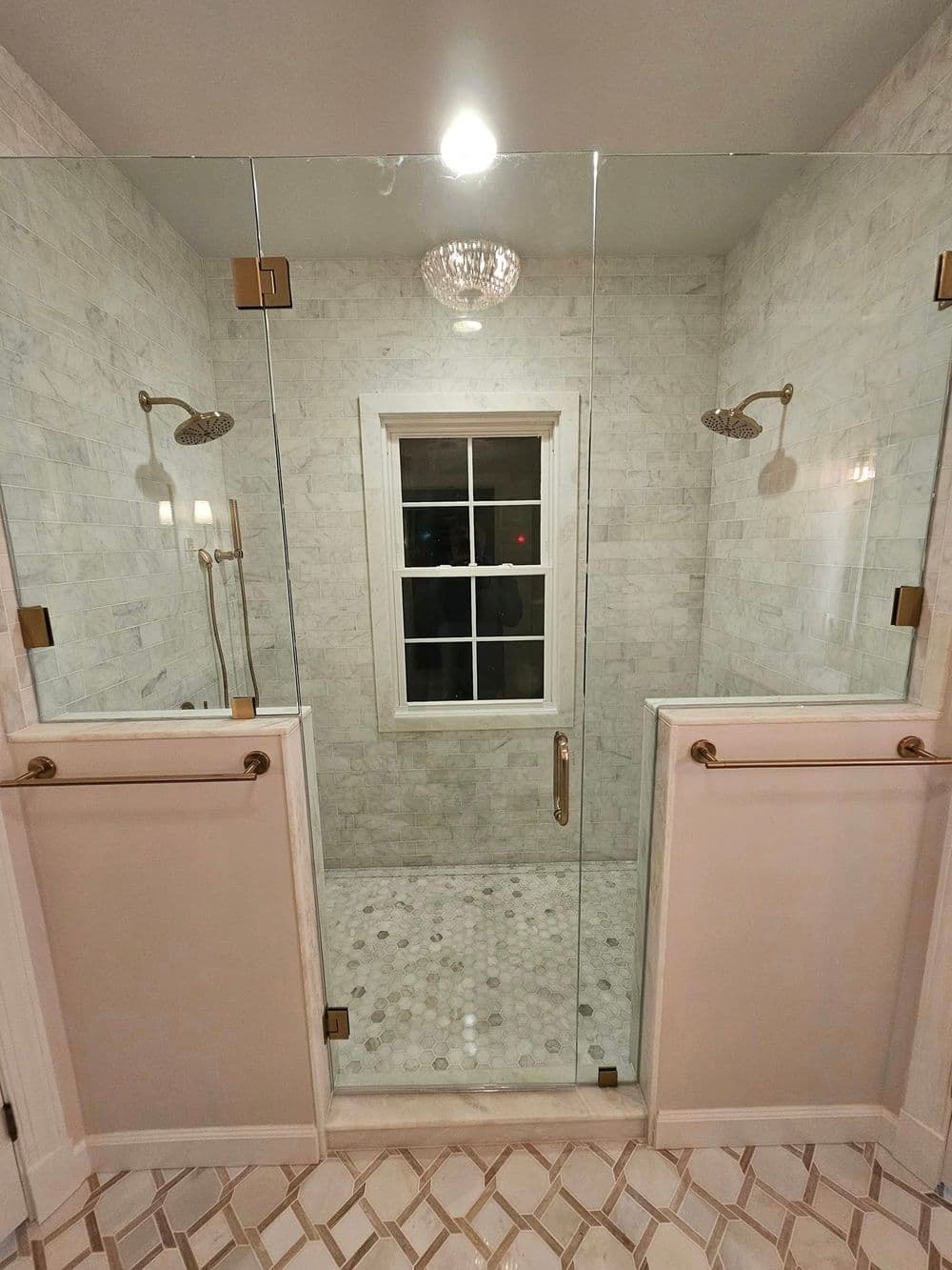 Modern walk-in shower with glass doors, marble tiles, and elegant fixtures in a bright bathroom.
