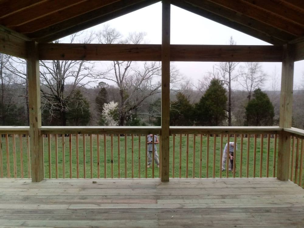 View from a wooden porch overlooking a green yard and trees in early spring.